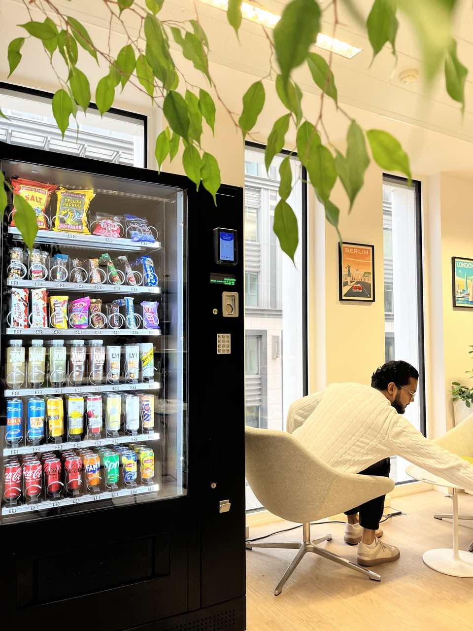 Un distributeur KM Vending installé dans un espace de travail, à côté d’un coin salon